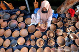 Produk UMKM Gerabah. Pengrajin Usaha Mikro, Kecil, dan Menengah (UMKM) menata hasil kerajinan gerabah dari tanah liat untuk dijajakan di Banda Aceh, Aceh, Jumat (16/7/2021). Berbagai jenis alat memasak hasil kerajinan dari tanah liat yang didatangkan dari Kabupaten Bireuen tersebut dijual antara Rp15.000 hingga Rp100.000 per unit. Antara Aceh/Irwansyah Putra