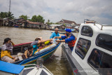 Kasat Polair Polresta Banjarmasin AKP Christugus Lirens (kanan) menyerahkan daging kurban kepada warga di Sungai Barito, Banjarmasin, Kalimantan Selatan, Rabu (21/7/2021). Satuan Polisi Air (Satpolair) Polresta Banjarmasin membagikan daging kurban pada H+2 Hari Raya Idul Adha 1442 H dengan cara membagikan langsung kepada warga yang beraktivitas di alur Sungai Barito untuk menghindari terjadinya kerumunan warga serta meminimalisir penyebaran COVID-19. Foto Antaranews Kalsel/Bayu Pratama S.