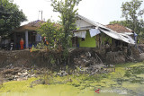 Warga melihat kondisi rumah yang rusak akibat longsor di desa Kertasmaya, Indramayu, Jawa Barat, Sabtu (24/7/2021). Pergerakan tanah yang terjadi di bantaran Sungai Cimanuk tersebut telah menyebabkan tiga rumah warga rusak dan penghuninya terpaksa mengungsi. ANTARA FOTO/Dedhez Anggara/agr