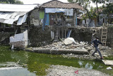 Warga melihat kondisi rumah yang rusak akibat longsor di desa Kertasmaya, Indramayu, Jawa Barat, Sabtu (24/7/2021). Pergerakan tanah yang terjadi di bantaran Sungai Cimanuk tersebut telah menyebabkan tiga rumah warga rusak dan penghuninya terpaksa mengungsi. ANTARA FOTO/Dedhez Anggara/agr