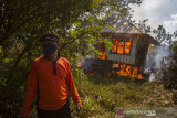 Warga berada di dekat pondok yang terbakar akibat kebaran lahan di kawasan Landasan Ulin Timur, Banjarbaru, Kalimantan Selatan, Senin (26/7/2021). Kebakaran hutan dan lahan (Karhutla) mulai terjadi di sejumlah wilayah Kalimantan Selatan yang mendekati permukiman penduduk.Foto Antaranews Kalsel/Bayu Pratama S.