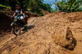 Warga menggunakan roda dua melintas di jalan yang longsor di Desa Banjarsari, Lebak, Banten, Jumat (6/8/2021). Hujan deras yang mengguyur daerah tersebut mengakibatkan jalan antardesa tertimbun longsor pada Rabu (5/8/2021) malam, dikhawatirkan terjadi longsor kembali jika hujan karena tanah yang masih labil. (ANTARA FOTO/Muhammad Bagus Khoirunas/foc).