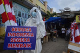 Seorang anggota Satlantas Polresta Bandar Lampung menggunakan kostum pocong saat sosialisasi bahaya COVID-19 di sejumlah Pasar tradisional di Bandar Lampung, Lampung, Jumat (6/8/2021). Satlantas Polresta Bandar Lampung menggunakan kostum pocong dan berperan sebagai virus Corona serta tenaga kesehatan dalam sosialisasi protokol kesehatan (prokes) COVID-19 agar masyarakat tahu dampak yang terjadi saat mengabaikan prokes. ANTARA FOTO/Ardiansyah/foc.
