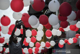 Warga memasang hiasan balon merah putih di Gang Pasir Reuma, Coblong, Bandung, Jawa Barat, Sabtu (14/8/2021). Warga berinisiatif melakukan swadaya masyarakat untuk menghias gangnya demi memeriahkan HUT ke-76 RI. ANTARA FOTO/Raisan Al Farisi/agr