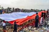 Sejumlah pegiat lingkungan yang tergabung dalam komunitas Republik Aer membentangkan bendera merah putih di Tempat Pembuangan Akhir Sampah (TPAS) Cianggir, Kota Tasikmalaya, Jawa Barat, Minggu (15/8/2021). Pembentangan bendera merah putih raksasa di TPAS tersebut dilakukan dalam rangkaian acara menyambut peringatan HUT Kemerdekaan ke-76 RI, sekaligus mengampanyekan kepedulian terhadap lingkungan dan menjaga ekosistem di masa pandemi COVID-19 serta memupuk rasa nasionalisme. ANTARA FOTO/Adeng Bustomi/agr