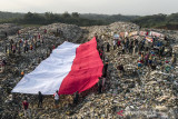 Foto udara pembentangan bendera merah putih oleh sejumlah pegiat lingkungan yang tergabung dalam komunitas Republik Aer di Tempat Pembuangan Akhir Sampah (TPAS) Cianggir, Kota Tasikmalaya, Jawa Barat, Minggu (15/8/2021). Pembentangan bendera merah putih raksasa di TPAS tersebut dilakukan dalam rangkaian acara menyambut peringatan HUT Kemerdekaan ke-76 RI, sekaligus mengampanyekan kepedulian terhadap lingkungan dan menjaga ekosistem di masa pandemi COVID-19 serta memupuk rasa nasionalisme. ANTARA FOTO/Adeng Bustomi/agr