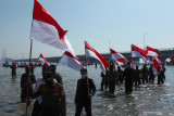 Petugas Satpol PP memegang bendera Merah Putih saat mengikuti upacara bendera di kawasan Jembatan Suramadu, Surabaya, Jawa Timur, Selasa (17/8/2021). Kegiatan yang digelar oleh Batalyon Infanteri 5 Marinir (Yonif 5 Mar) TNI Angkatan Laut dan diikuti pelajar, masyarakat pesisir serta Aparatur Sipil Negara (ASN) itu untuk memperingati HUT Ke-76 Kemerdekaan Republik Indonesia.  Antara Jatim/Didik Suhartono/zk