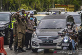 Petugas gabungan memeriksa dokumen syarat melakukan perjalanan pengemudi yang hendak memasuki Kota Banjarmasin saat pemberlakuan pengetatan di Jalan Ahmad Yani, Banjarmasin, Kalimantan Selatan, Kamis (19/8/2021). Pemerintah Kota Banjarmasin bersama Kodim 1007/Banjarmasin dan Polresta Banjarmasin dalam pelaksanaan PPKM Level 4 melakukan pengetatan kepada masyarakat yang hendak memasuki Kota Banjarmasin guna menekan penyeberan dan penularan COVID-19. Foto Antaranews Kalsel/Bayu Pratama S.