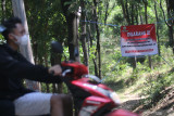 Warga melintas di depan akses masuk jalur pendakian gunung Klotok yang ditutup di Kota Kediri, Jawa Timur, Selasa (31/8/2021). Jalur masuk pendakian menuju gunung Klotok yang di puncaknya terdapat candi Klotok tersebut ditutup untuk umum guna menanggulangi penyebaran COVID-19. Antara Jatim/Prasetia Fauzani/zk