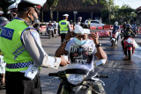 Pengendara mengenakan masker yang diberikan petugas saat penyekatan di kawasan Mengwi, Badung, Bali, Selasa (31/8/2021). Kapolri Jenderal Pol Listyo Sigit Prabowo meminta penyekatan antar wilayah provinsi maupun kabupaten/kota di Bali terus dimaksimalkan sebagai salah satu upaya pengendalian pandemi COVID-19. ANTARA FOTO/Fikri Yusuf/nym.