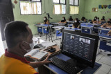 Seorang Guru (kiri) menerangkan materi pembelajaran kepada murid SMPN 2 Bekasi secara hybrid atau kombinasi antara tatap muka terbatas dengan pembelajaran secara daring di Bekasi, Jawa Barat, Rabu (1/9/2021). Sebanyak 66 SMP menggelar Pembelajaran Tatap Muka (PTM) dengan jumlah 50 persen murid dan menerapkan protokol kesehatan. ANTARA FOTO/ Fakhri Hermansyah/hp.