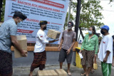 Petugas menyerahkan bantuan paket sembako kepada warga saat penyaluran bantuan di Pantai Kuta, Badung, Bali, Minggu (12/9/2021). Desa Adat Kuta menyalurkan bantuan paket sembako yang terkumpul dari program donasi yang dibuka dengan menggalang donasi dari para pengusaha dan masyarakat umum untuk membantu ratusan masyarakat Kuta khususnya para pekerja sektor pariwisata yang kondisi perekonomiannya terdampak pandemi COVID-19. ANTARA FOTO/Fikri Yusuf/nym.