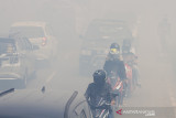 Sejumlah pengendara motor melintas di jalan yang diselimuti kabut asap kebakaran lahan di Kecamatan Liang Anggang, Banjarbaru, Kalimantan Selatan, Selasa (21/9/2021). Kencangnya angin di lokasi yang terbakar membuat api dengan cepat membakar lahan yang diperkirakan mencapai puluhan hektare hingga kini BPBD Kota Banjarbaru dibantu relawan pemadam kebakaran Kota Banjarmasin berupaya memadamkan api yang mendekati permukiman penduduk di daerah setempat. Foto Antaranews Kalsel/Bayu Pratama S.