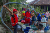 Petugas gabungan dari Palang Merah Indonesia (PMI) mengisi air bersih saat pendistribusian air secara gratis di Desa Kertasari, Pangkalan, Karawang, Jawa Barat, Sabtu (25/9/2021). PMI bersama Tagana mendistribusikan sebanyak 31 ribu liter air bersih untuk warga yang mengalami kesulitan air bersih sebanyak 595 Kartu Keluarga (KK). ANTARA FOTO/M Ibnu Chazar/agr