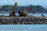 Sejumlah alat berat menimbun batu di tengah laut untuk proyek pembangunan dermaga pelabuhan di Sanur, Denpasar, Bali, Kamis (30/9/2021). Pembangunan dermaga pelabuhan di kawasan itu menjadi salah satu simpul transportasi laut untuk penyeberangan kapal-kapal kecil ke wilayah yang dikenal segitiga emas yakni Sanur, Nusa Penida, dan Nusa Ceningan, dengan target selesai pada tahun 2022. ANTARA FOTO/Nyoman Hendra Wibowo/nym.