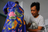 Perajin menata kain batik dengan desain modern atau kontemporer bermotif ikan koi sebelum diekspor ke Jepang dan Singapura di Studio Batik Lembayung, Malang, Jawa Timur, Jumat (1/10/2021). Pengusaha batik setempat mengatakan desain batik modern yang memadukan keunikan motif hewan simbolik serta warna pastel tersebut dalam setahun terakhir menjadi tren karena disukai para konsumen berusia muda. Antara Jatim/Ari Bowo Sucipto/zk.