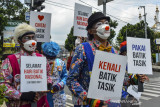 Sejumlah anggota Komunitas Badut Tasik (Battik) menunjukan poster menyerukan mencintai batik di Kota Tasikmalaya, Jawa Barat, Jumat (1/10/2021). Aksi Komunitas Battik itu dilakukan menjelang Hari Batik Nasional pada 2 Oktober, untuk mendorong kebangkitan pelaku usaha ekonomi kreatif khususnya perajin batik serta mengkampanyekan kecintaan terhadap batik yang diakui UNESCO sebagai warisan budaya. ANTARA FOTO/Adeng Bustomi/agr