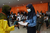 Petugas menyerahkan kartu vaksin kepada peserta saat vaksinasi massal COVID-19 yang digelar Ikatan Keluarga Mahasiswa Universitas Indonesia Madiun, Yayasan Women Centre Madiun dan Polres Madiun Kota di sebuah pusat perbelanjaan di Kota Madiun, Jawa Timur, Minggu (3/10/2021). Kegiatan vaksinasi massal tersebut menyediakan 1.250 dosis vaksin COVID-19 yang diikuti pelajar dan masyarakat umum. Antara Jatim/Siswowidodo/zk.