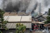 Asap hitam mengepul dari atap sebuah pabrik tekstil yang terbakar di Cijerah, Bandung, Jawa Barat, Senin (4/10/2021). Petugas menyatakan, kebakaran tersebut diduga oleh tetesan oli panas yang jatuh ke tumpukan kain. ANTARA FOTO/Raisan Al Farisi/agr