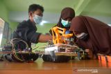 SISWA MTsN CIPTAKAN ROBOT MEDIS COVID-19. Siswa mengenakan masker memasang komponen pada mobil robot sebelum uji coba di Sekolah Madrasyah Tsanawiyah Negeri-1 (MTsN) Banda Aceh, Aceh, Jumat (8/10/2021). Pembuatan mobil robot yang diperuntukkan membantu tugas tenaga medis dalam penanganan COVID-19 itu merupakan persiapan untuk mengikuti kompetisi Robitik Madrasyah Tingkat Nasional tahun 2021 dengan tema Robots for Global Pandemic yang dijadwalkan berlangsung 16-17 Oktober 2021 di Kota Tangerang, Provinsi Banten. ANTARA FOTO/Ampelsa.
