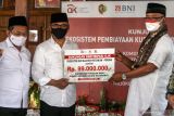 Ketua Dewan Komisioner Otoritas Jasa Keuangan (OJK) Wimboh Santoso (tengah) menyerahkan secara simbolis bantuan KUR kepada Pimpinan Pondok Pesantren Segoro Agung, K.H. Abdul Adzim Alwi (kanan) dalam acara dialog dengan petani porang di Pondok Pesantren Segoro Agung, Mojokerto, Jawa Timur,  Jumat (8/10/2021).  Otoritas Jasa Keuangan terus mendukung upaya kolaboratif dan sinergis antara Pemerintah Daerah, perbankan dan stakeholder terkait untuk memberikan dukungan dan memperluas akses keuangan bagi petani porang melalui pengembangan penyaluran Kredit Usaha Rakyat (KUR) yang diharapkan dapat mempercepat pemulihan ekonomi nasional dan mendorong peningkatan produktivitas dan kualitas hasil pertanian. Antara Jatim/Umarul Faruq/zk.