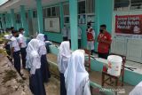 Relawan PMI sedang memberikan edukasi protokol kesehatan (prokes) saat ujicoba Pembelajaran Tatap Muka (PTM) kepada siswa salah satu sekolah menengah pertama (SMP) di Sukabumi, Jawa Barat. (Foto Antara/HO/PMI/IFRC).