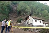 Petugas mengamati rumah yang rusak tertimbun longsoran bukit akibat gempa di kawasan Trunyan, Kintamani, Bangli, Bali, Sabtu (16/10/2021). Gempa bumi dengan magnitudo 4,8 SR yang terjadi di darat pada jarak delapan kilometer barat laut Karangasem dengan kedalaman 10 km pada Sabtu (16/10) pukul 04.18 Wita mengakibatkan sejumlah bangunan di Bali rusak dan tiga orang meninggal dunia. ANTARA FOTO/Fikri Yusuf/nym.