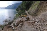 Foto udara petugas yang menggunakan alat berat membersihkan material longsoran bukit akibat gempa bumi Karangasem Bali yang menutup jalan di kawasan Kintamani, Bangli, Bali, Minggu (17/10/2021). Hingga Minggu (17/10) petang, ratusan KK yang tinggal di beberapa desa di wilayah Kecamatan Kintamani seperti Desa Trunyan masih terisolir karena sejumlah titik di satu-satunya akses jalur darat yang menghubungkan wilayah desa mereka menuju Kota Bangli masih tertimbun material longsor akibat gempa bumi 4,8 SR pada Sabtu (16/10) dini hari. ANTARA FOTO/Fikri Yusuf/nym.