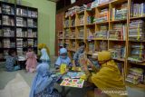 PERINGATAN HARI PERPUSTAKAAN SEKOLAH INTERNASIONAL DENGAN PROKES. Guru memperkenalkan berbagai buku pelajaran kepada murid dan dilanjutkan dengan kegiatan mewarnai di perpustakaan sekolah  TK Rumah Baca  Anak Nanggroe (Ruman) Banda Aceh, Aceh, Senin (18/10/2021). Kegiatan murid tersebut dalam rangka memperingati Hari Perpustakaan Sekolah Internasional dengan tujuan membangun kesadaran budaya literasi kepada pelajar, termasuk anak usia dini.ANTARA FOTO/Ampelsa.