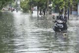 Siswa mendorong motor untuk menerobos genangan air di Rawalumbu, Bekasi, Jawa Barat, Senin (18/10/2021). Intesitas hujan yang tinggi di wilayah tersebut menyebabkan genangan air setinggi 80 cm akibat saluran drainase yang buruk. ANTARA FOTO/ Fakhri Hermansyah/rwa.
