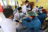 Petugas medis memeriksa kondisi kesehatan pelajar sebelum mendapatkan suntikan vaksin COVID-19 di SMA Negeri 1 Plosoklaten, Kediri, Jawa Timur, Senin (19/10/2021). Vaksinasi COVID-19 untuk pelajar secara massal yang diselenggarakan serentak di sejumlah sekolah tersebut guna mewujudkan kekebalan kelompok sebagai persiapan pelaksanaan pembelajaran tatap muka. Antara Jatim/Prasetia Fauzani/zk