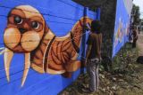 Seniman menyelesaikan pembuatan grafiti di Mutiara Kapitan, Sukatani, Depok, Jawa Barat, Minggu (17/10/2021). Aksi melukis grafiti yang bertema 