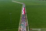 Foto udara peserta membentangkan bendera Merah Putih saat kirab santri di Desa Ciwulan, Telagasari, Karawang, Jawa Barat, Senin (25/10/2021). Kegiatan yang diikuti ratusan santri, Barisan Ansor Serbaguna (Banser) dan Ikatan Pelajar Nahdlatul Ulama (IPNU) itu dalam rangka memperingati hari lahir PCNU Karawang ke-84 dan Hari Santri Nasional 2021. ANTARA FOTO/M Ibnu Chazar/agr