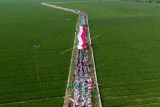 Foto udara peserta membentangkan bendera Merah Putih saat kirab santri di Desa Ciwulan, Telagasari, Karawang, Jawa Barat, Senin (25/10/2021). Kegiatan yang diikuti ratusan santri, Barisan Ansor Serbaguna (Banser) dan Ikatan Pelajar Nahdlatul Ulama (IPNU) itu dalam rangka memperingati hari lahir PCNU Karawang ke-84 dan Hari Santri Nasional 2021. ANTARA FOTO/M Ibnu Chazar/rwa.