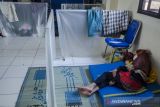 Warga beristirahat pada pengungsian banjir di Balai Desa Dayeuhkolot, Kabupaten Bandung, Jawa Barat, Rabu (3/11/2021). Pengungsian yang dibuat memiliki sekat untuk mencegah terpapar COVID-19 tersebut telah diisi sedikitnya 32 jiwa sedangkan sebagian warga masih bertahan di rumah yang terdampak banjir Bandung Selatan. ANTARA FOTO/Novrian Arbi/agr