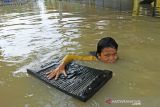 Seorang anak bermain air saat banjir di Desa Karangligar, Karawang, Jawa Barat, Jumat (5/11/2021). Banjir yang melanda di wilayah itu disebabkan meluapnya air sungai Cibeet karena tingginya intensitas hujan yang mengakibatkan ratusan rumah terendam banjir. ANTARA FOTO/M Ibnu Chazar/agr