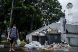 Warga berjalan di dekat tumpukan sampah di tempat penampungan sementara sampah kawasan Alun-Alun, Bandung, Jawa Barat, Minggu (7/11/2021). Sampah yang berada di tempat pembuangan sementara kawasan  Bandung Raya belum bisa terangkut sejak dua hingga tiga hari lalu ke tempat pembuangan akhir (TPA) Sarimukti akibat diduga keterlambatan pengiriman bahan bakar minyak (BBM) untuk alat berat yang menggangu operasional di TPA Sarimukti. ANTARA FOTO/Novrian Arbi/agr