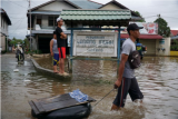 Warga melintasi Jalan Lintas Melawi yang terdampak banjir di Ladang, Kabupaten Sintang, Kalimantan Barat, Jumat (12/11/2021). Banjir yang melanda 12 kecamatan tersebut belum juga surut selama tiga pekan terakhir akibat curah hujan yang tinggi, sementara pendistribusian bantuan masih terkendala di sejumlah wilayah karena sulitnya akses menuju lokasi. ANTARA FOTO/Abraham Mudito/app/aww.