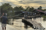 Sejumlah pengendara motor melintas di atas jembatan darurat di jalan utama Sintang-Putussibau yang terendam banjir di Kabupaten Sintang, Kalimantan Barat, Sabtu (13/11/2021). Penduduk setempat membangun jembatan darurat tersebut untuk membantu pejalan kaki, pengendara motor dan pesepeda yang melintasi jalan yang terendam banjir. ANTARA FOTO/Jane Elisabeth Wuysang/JHW/wsj.