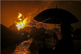 Warga menonton kobaran api yang terlihat di Kilang Pertamina Internasional (KPI) RU IV Cilacap, Jawa Tengah, Minggu (14/11/2021) dini hari. Tangki 36 T 102 terbakar pada Sabtu (13/11/2021) pukul 19.10 WIB itu berisi komponen pertalite. ANTARA FOTO/Idhad Zakaria/foc.