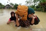 Warga memikul harta bendanya untuk keluar dari kepungan banjir di Desa Hagu, Kecamatan Matang Kuli, Aceh Utara, Aceh, Rabu (17/11/2021). Meluapnya Sungai Pirak dan Kereuto mengakibatkan 30 desa di empat kecamatan Aceh Utara terendam banjir hingga 150 centimeter dan mengakibatkan sebanyak 2.383 jiwa dilaporkan terdampak banjir. ANTARA FOTO/Rahmad