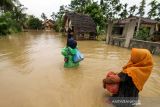 Warga memikul harta bendanya untuk keluar dari kepungan banjir di Desa Hagu, Kecamatan Matang Kuli, Aceh Utara, Aceh, Rabu (17/11/2021). Meluapnya Sungai Pirak dan Kereuto mengakibatkan 30 desa di empat kecamatan Aceh Utara terendam banjir hingga 150 centimeter dan mengakibatkan sebanyak 2.383 jiwa dilaporkan terdampak banjir. ANTARA FOTO/Rahmad