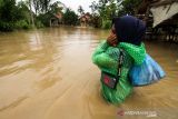 Warga memikul harta bendanya untuk keluar dari kepungan banjir di Desa Hagu, Kecamatan Matang Kuli, Aceh Utara, Aceh, Rabu (17/11/2021). Meluapnya Sungai Pirak dan Kereuto mengakibatkan 30 desa di empat kecamatan Aceh Utara terendam banjir hingga 150 centimeter dan mengakibatkan sebanyak 2.383 jiwa dilaporkan terdampak banjir. ANTARA FOTO/Rahmad