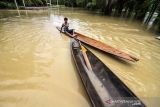 Warga memikul harta bendanya untuk keluar dari kepungan banjir di Desa Hagu, Kecamatan Matang Kuli, Aceh Utara, Aceh, Rabu (17/11/2021). Meluapnya Sungai Pirak dan Kereuto mengakibatkan 30 desa di empat kecamatan Aceh Utara terendam banjir hingga 150 centimeter dan mengakibatkan sebanyak 2.383 jiwa dilaporkan terdampak banjir. ANTARA FOTO/Rahmad