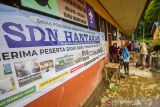 Sejumlah murid membersihkan ruang kelas SD Negeri Hantakan dari lumpur akibat meluapnya sungai Hantakan di Kecamatan Hantakan, Kabupaten Hulu Sungai Tengah, Kalimantan Selatan, Jumat (19/11/2021). Dampak meluapnya sungai Hantakan tersebut mengakibatkan satu jembatan darurat hanyut terbawa arus serta satu sekolah dasar dipenuhi lumpur.Foto Antaranews Kalsel/Bayu Pratama S.