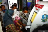 Seorang warga dibantu petugas mencetak Kartu Identitas Anak menggunakan mesin Anjungan Dukcapil Mandiri (ADM) Dinas Kependudukan dan Pencatatan Sipil (Dispendukcapil) di Mal Pelayanan Publik Kabupaten Madiun, Jawa Timur, Rabu (24/11/2021). Dispendukcapil Kabupaten Madiun meningkatkan layanan di mal pelayanan publik antara lain menyediakan ADM guna memberikan kemudahan, kecepatan dan kenyamanan warga yang mengurus dokumen kependudukan. Antara Jatim/Siswowidodo