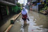 Seorang pelajar berjalan melintasi banjir yang menggenangi permukiman di Kampung Bojongasih, Dayeuhkolot, Kabupaten Bandung, Jawa Barat, Jumat (26/11/2021). Hujan dengan intensitas tinggi pada Kamis (25/11/2021) membuat ratusan rumah di Kecamatan Baleendah dan Dayeuhkolot terendam banjir luapan sungai Citarum setinggi 50 sentimeter hingga satu meter. ANTARA FOTO/Raisan Al Farisi/agr
