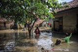 Warga melintasi banjir di Kampung Bojongasih, Dayeuhkolot, Kabupaten Bandung, Jawa Barat, Jumat (26/11/2021). Hujan dengan intensitas tinggi pada Kamis (25/11/2021) membuat ratusan rumah di Kecamatan Baleendah dan Dayeuhkolot terendam banjir luapan sungai Citarum setinggi 50 sentimeter hingga satu meter. ANTARA FOTO/Raisan Al Farisi/agr