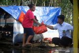 Petugas Perumdam Tirta Senentang Sintang (kanan) menyerahkan bantuan sembako untuk korban banjir di Sungai Rambai, Kabupaten Sintang, Kalimantan Barat, Kamis (25/11/2021). Perusahaan Umum Daerah Air Minum (Perumdam) Tirta Senentang mendistribusikan puluhan paket sembako yang merupakan kerjasama dengan Dewan Pimpinan Pusat dan Dewan Pimpinan Daerah Persatuan Perusahaan Air Minum se-Indonesia bagi korban banjir yang bermukim di hilir sungai di wilayah setempat. ANTARA FOTO/Jessica Helena Wuysang