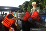 Direktur Perumdam Tirta Senentang Sintang Jane Elisabeth Wuysang (kiri) menyerahkan bantuan sembako untuk korban banjir di Sungai Rambai, Kabupaten Sintang, Kalimantan Barat, Kamis (25/11/2021). Perusahaan Umum Daerah Air Minum (Perumdam) Tirta Senentang mendistribusikan puluhan paket sembako yang merupakan kerjasama dengan Dewan Pimpinan Pusat dan Dewan Pimpinan Daerah Persatuan Perusahaan Air Minum se-Indonesia bagi korban banjir yang bermukim di hilir sungai di wilayah setempat. ANTARA FOTO/Jessica Helena Wuysang